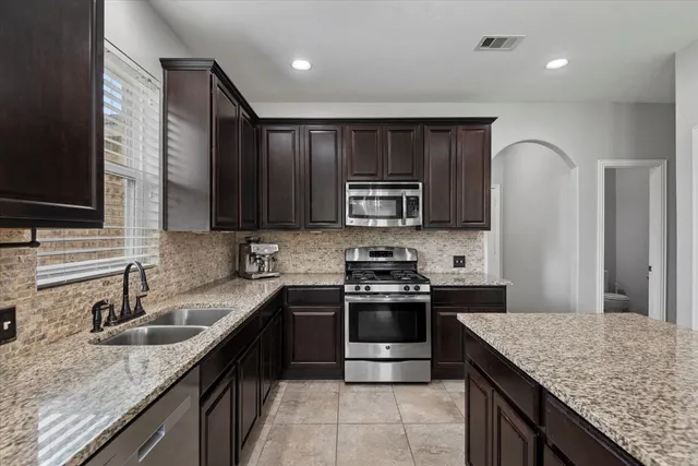 a kitchen with stainless steel appliances granite countertop a sink stove and refrigerator