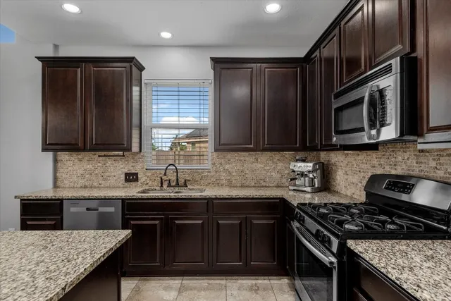 a kitchen with stainless steel appliances granite countertop a stove sink and cabinets