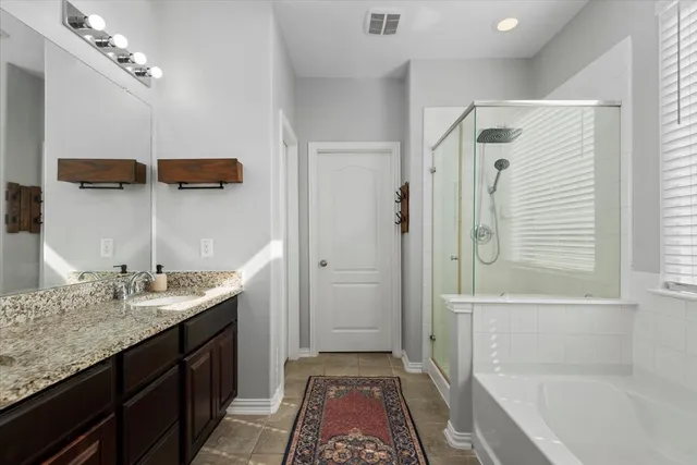 a bathroom with a granite countertop sink a mirror a vanity and a bathtub