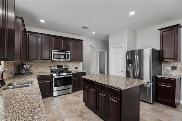 a kitchen with stainless steel appliances granite countertop a stove a sink dishwasher a refrigerator and a microwave oven with cabinets