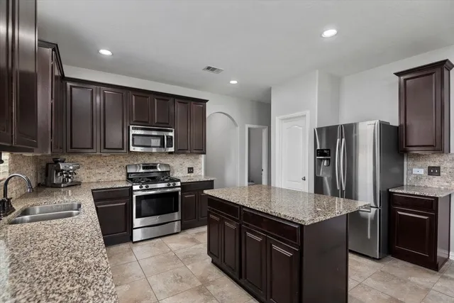 a kitchen with stainless steel appliances granite countertop a stove a sink dishwasher a refrigerator and a microwave oven with cabinets