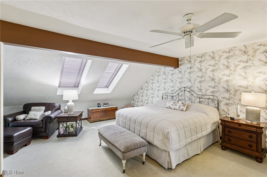 235 Solon Road, Unit D Chagrin Falls, OH 44022 - Photo 19 of 37 Primary second floor bedroom featuring a skylight, light carpet, beautiful wallpaper on one wall, and a ceiling fan