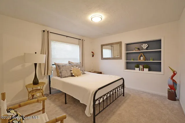 a bedroom with a bed a table and a large window