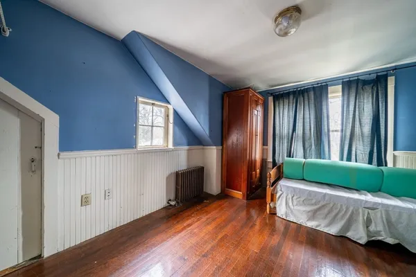 an empty room with wooden floor staircase and windows