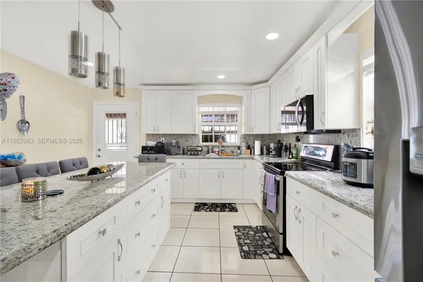 a kitchen with granite countertop stainless steel appliances a sink a stove and cabinets