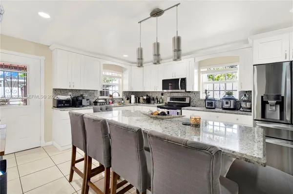 a kitchen with stainless steel appliances granite countertop a sink a stove a microwave a refrigerator a center island and chairs