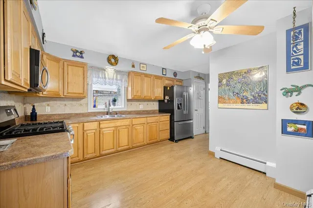 a kitchen with stainless steel appliances a refrigerator a sink dishwasher a oven with white cabinets and a dining table