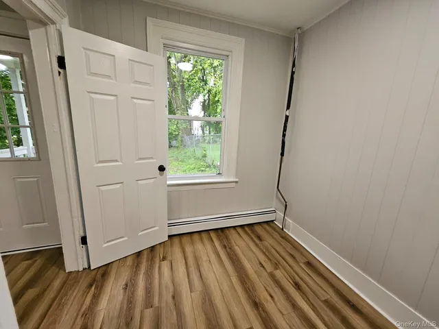 a view of empty room with wooden floor and fan