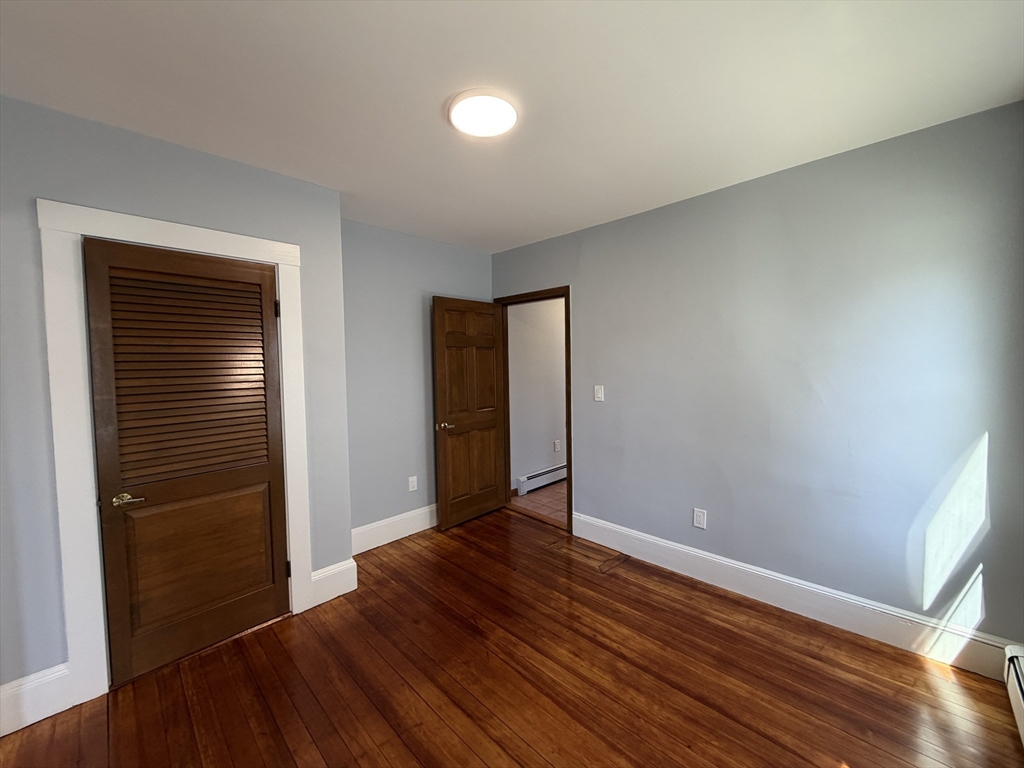117 Merrymount Road, Unit 1 Quincy, MA 02169 - Photo 7 of 12 an empty room with wooden floor and closet