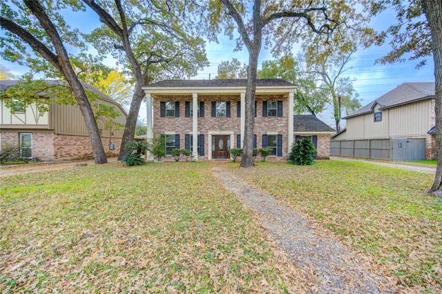 a view of a house with a yard and large tree