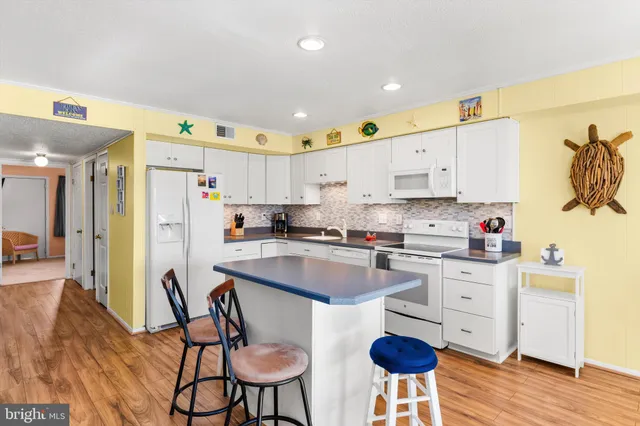 a kitchen with stainless steel appliances granite countertop a table chairs sink and cabinets