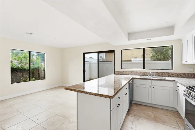 a large white kitchen with a sink large window and cabinets