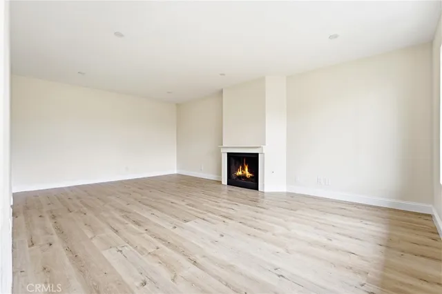 a view of an empty room with wooden floor and a fireplace