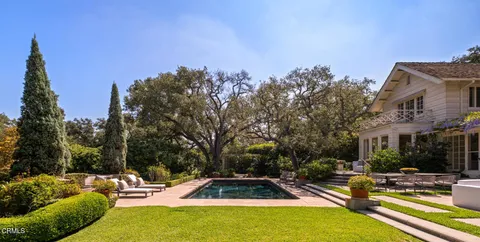 a view of swimming pool with outdoor seating and trees in the background