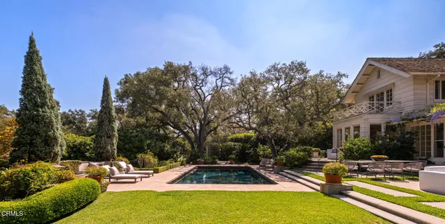 a view of swimming pool with outdoor seating and trees in the background