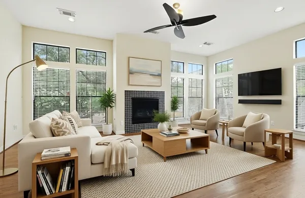 a living room with furniture floor to ceiling window hardwood floor and a flat screen tv