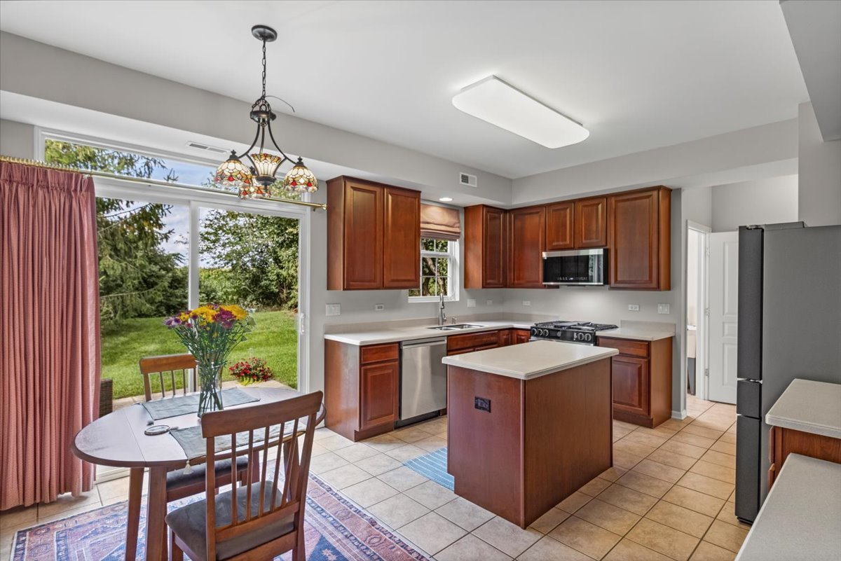 13544 Delaney Road Huntley, IL 60142 - Photo 8 of 21 a kitchen with stainless steel appliances granite countertop a stove top oven a sink dishwasher and a refrigerator with wooden floor