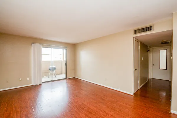 a view of an empty room with wooden floor and a window