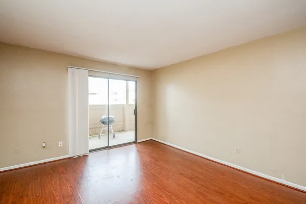 a view of an empty room with wooden floor and a window