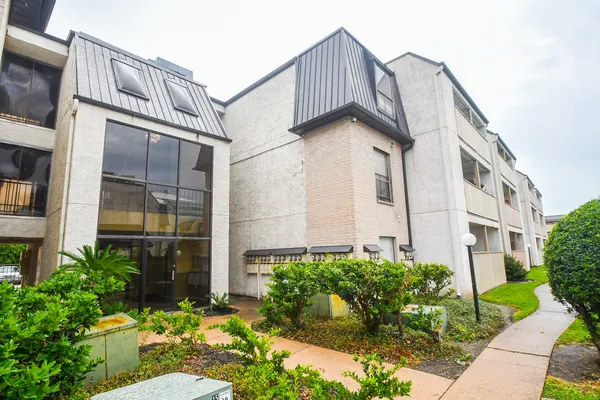 a view of a blue house with large windows and flower plants