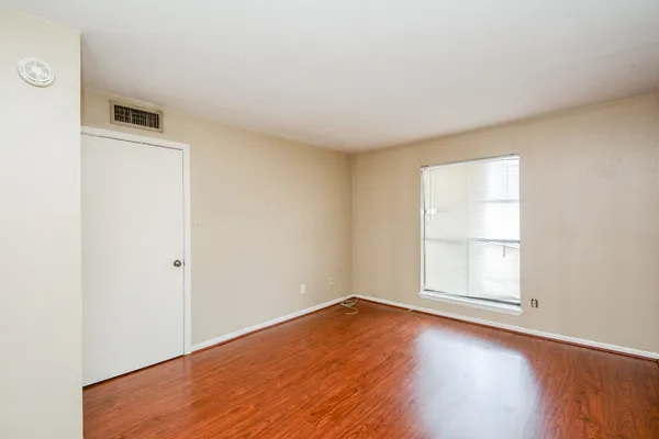 an empty room with wooden floor and window