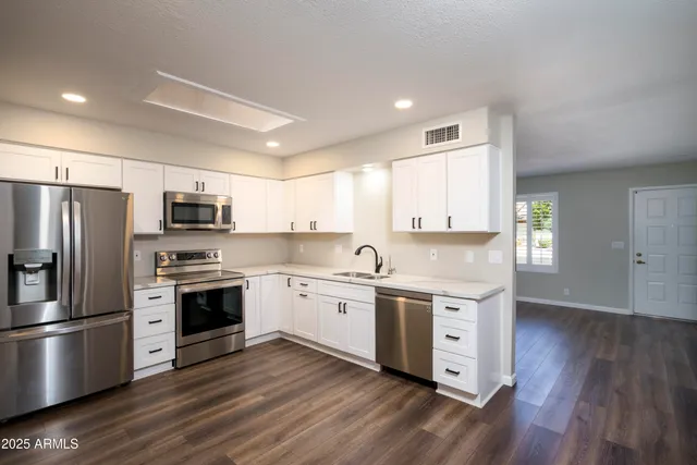 a kitchen with stainless steel appliances granite countertop a stove a sink dishwasher a refrigerator and a stove with wooden floors