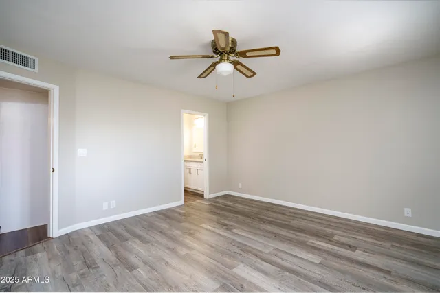 a view of empty room with wooden floor and ceiling fan