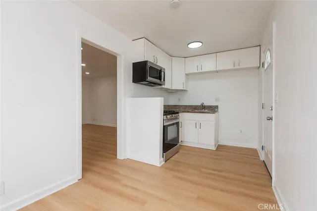 a kitchen with stainless steel appliances a stove a microwave cabinets and a window