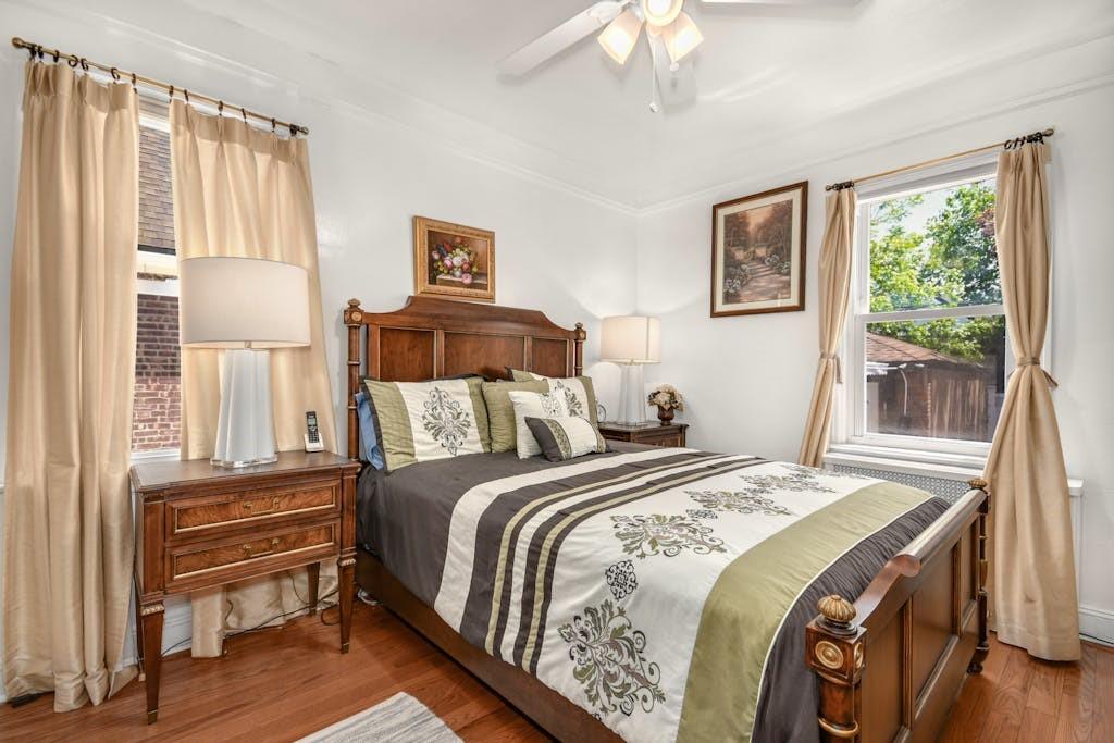 a bedroom with a bed next to a window with a flat tv screen