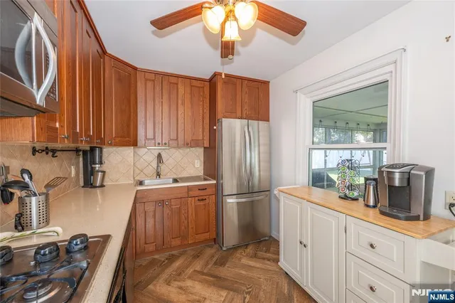 a kitchen with granite countertop a refrigerator a stove a sink dishwasher and wooden cabinets