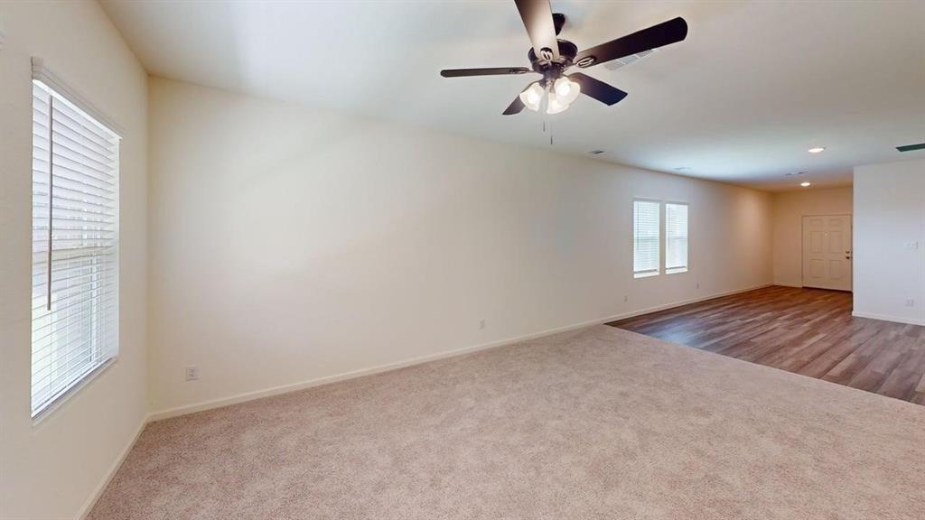 4529 Winecup Road Melissa, TX 75454 - Photo 6 of 29 Spacious room featuring neutral carpeting, a ceiling fan with integrated lighting, and multiple windows with blinds