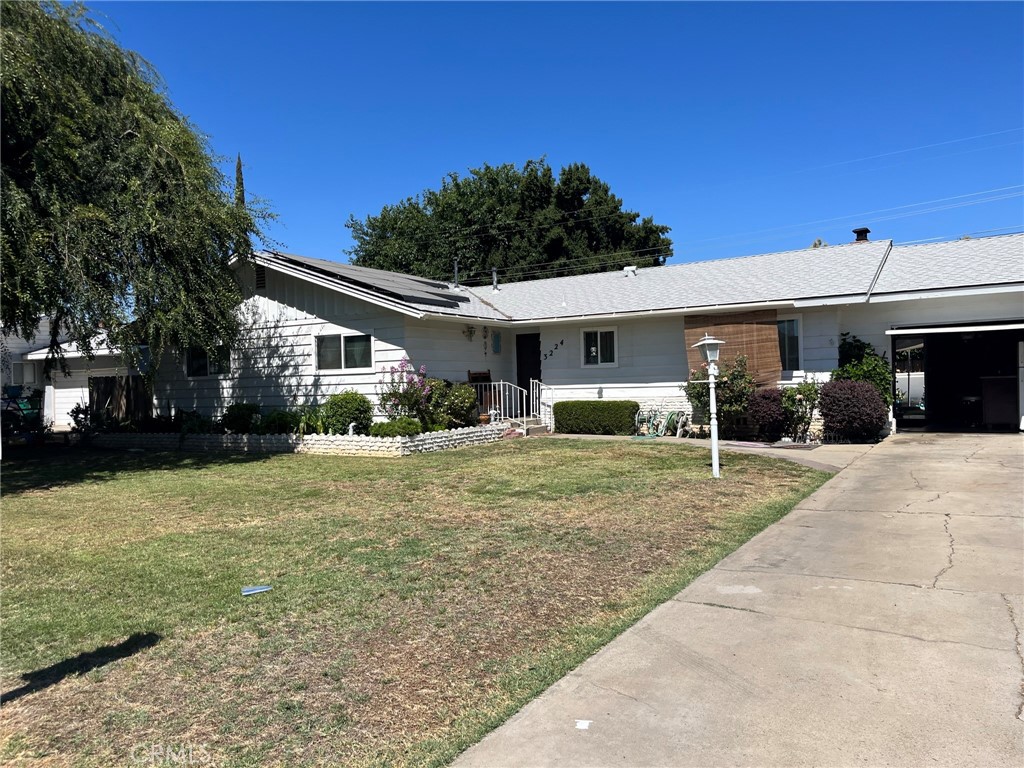 a view of a white house with a yard plants and palm trees