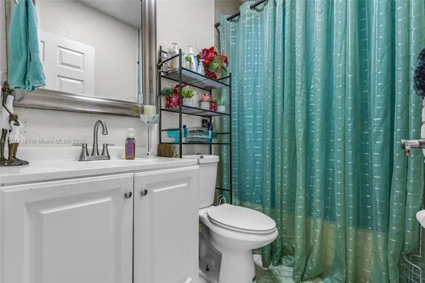 a bathroom with a toilet a sink and curtain