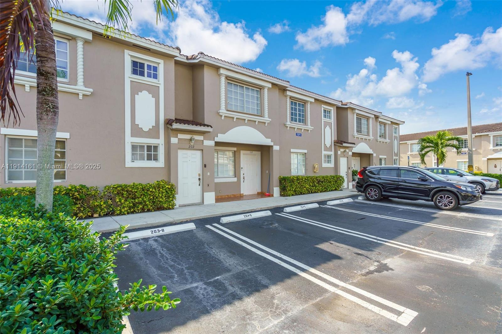 7271 Northwest 174th Terrace, Unit 202 Hialeah, FL 33015 - Photo 2 of 22 a front view of a house with a yard and outdoor seating