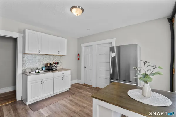 a kitchen with stainless steel appliances kitchen island granite countertop a refrigerator a sink a stove and white cabinets