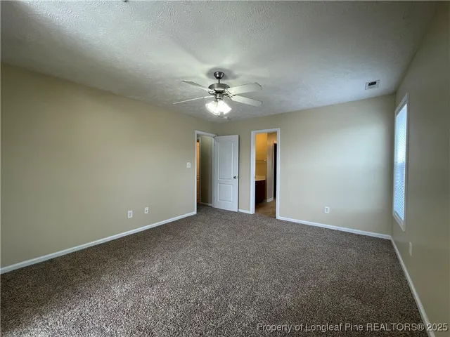an empty room with a ceiling fan and a window
