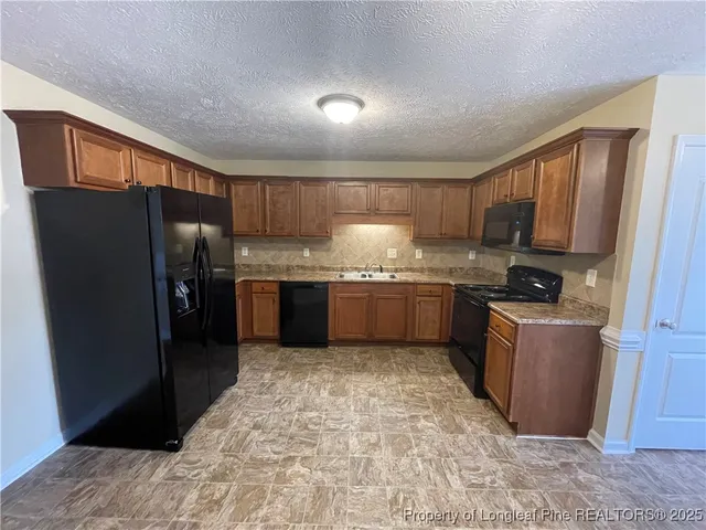 a kitchen with stainless steel appliances granite countertop a refrigerator stove and a sink