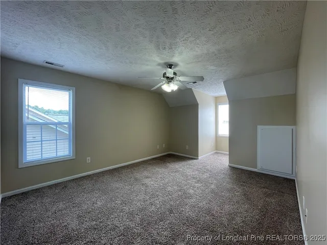 an empty room with chandelier fan and windows