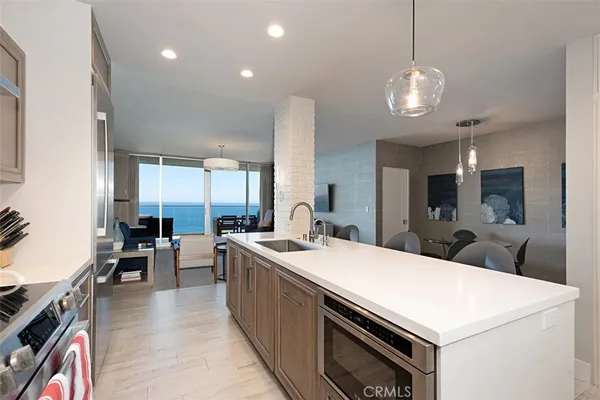 a large kitchen with kitchen island a white counter space a sink appliances and living room view