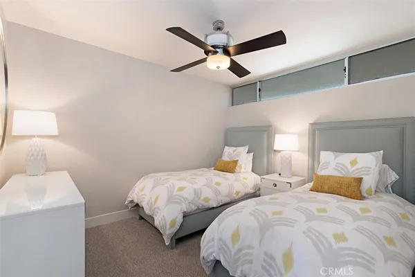 a bedroom with two separate beds and ceiling fan