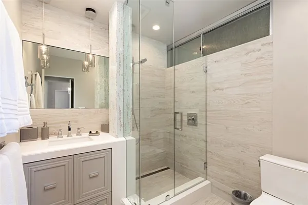 a bathroom with a shower sink vanity and toilet
