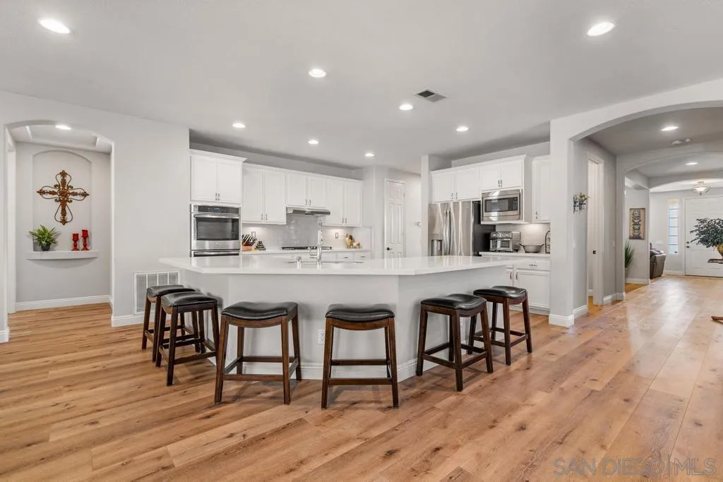 a kitchen with stainless steel appliances granite countertop a dining table chairs refrigerator microwave and cabinets