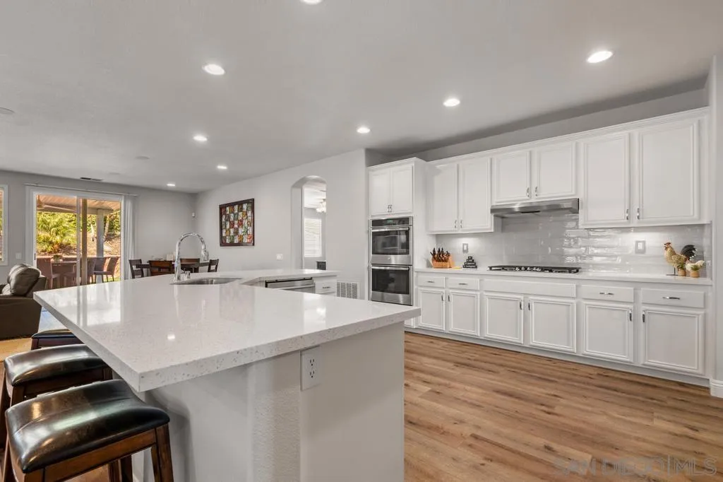 1253 Sunset Heights Road Escondido, CA 92026 - Photo 8 of 30 a large kitchen with kitchen island a stove a sink a refrigerator and white cabinets with wooden floor