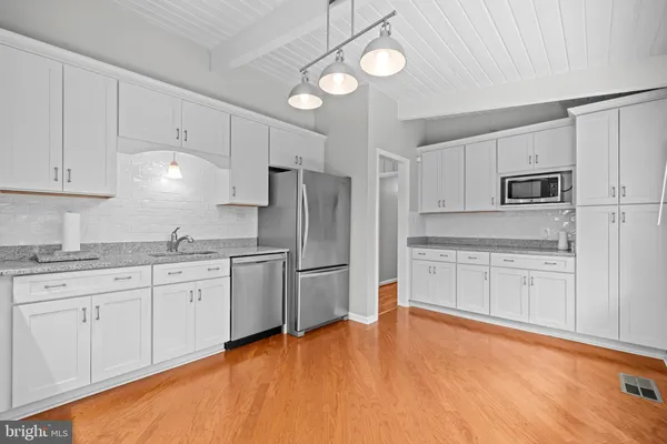 a kitchen with granite countertop a refrigerator sink and white cabinets