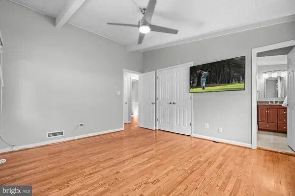 a view of empty room with wooden floor and fan