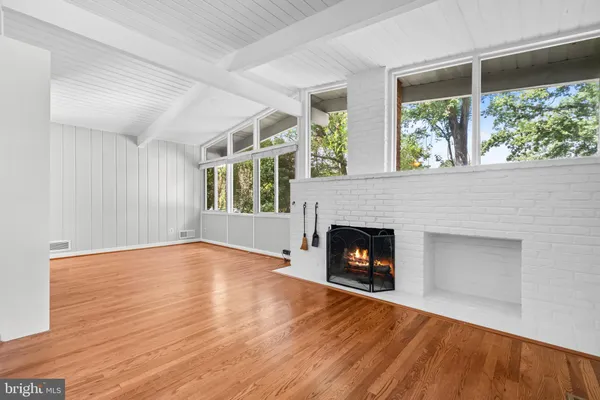 a view of an empty room with wooden floor fireplace and a window