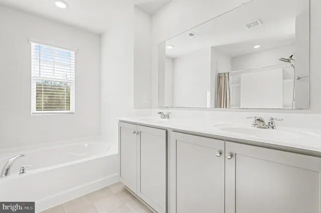 a bathroom with a bathtub a double vanity sink and a mirror