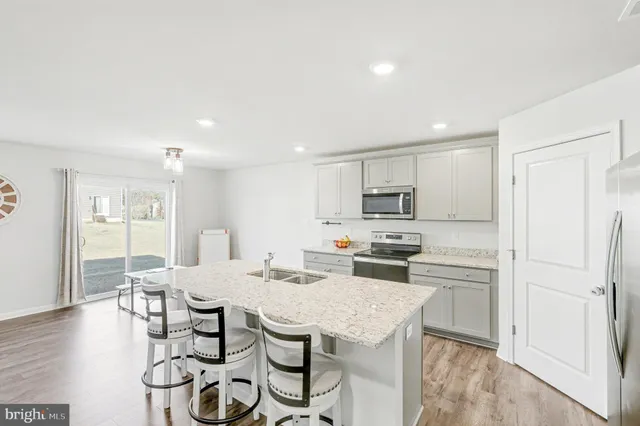 a kitchen with stainless steel appliances kitchen island granite countertop a dining table chairs and a refrigerator