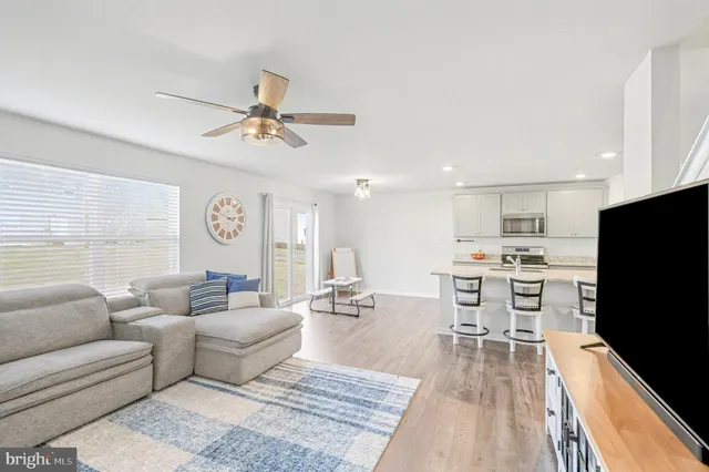 a living room with furniture a flat screen tv and kitchen view