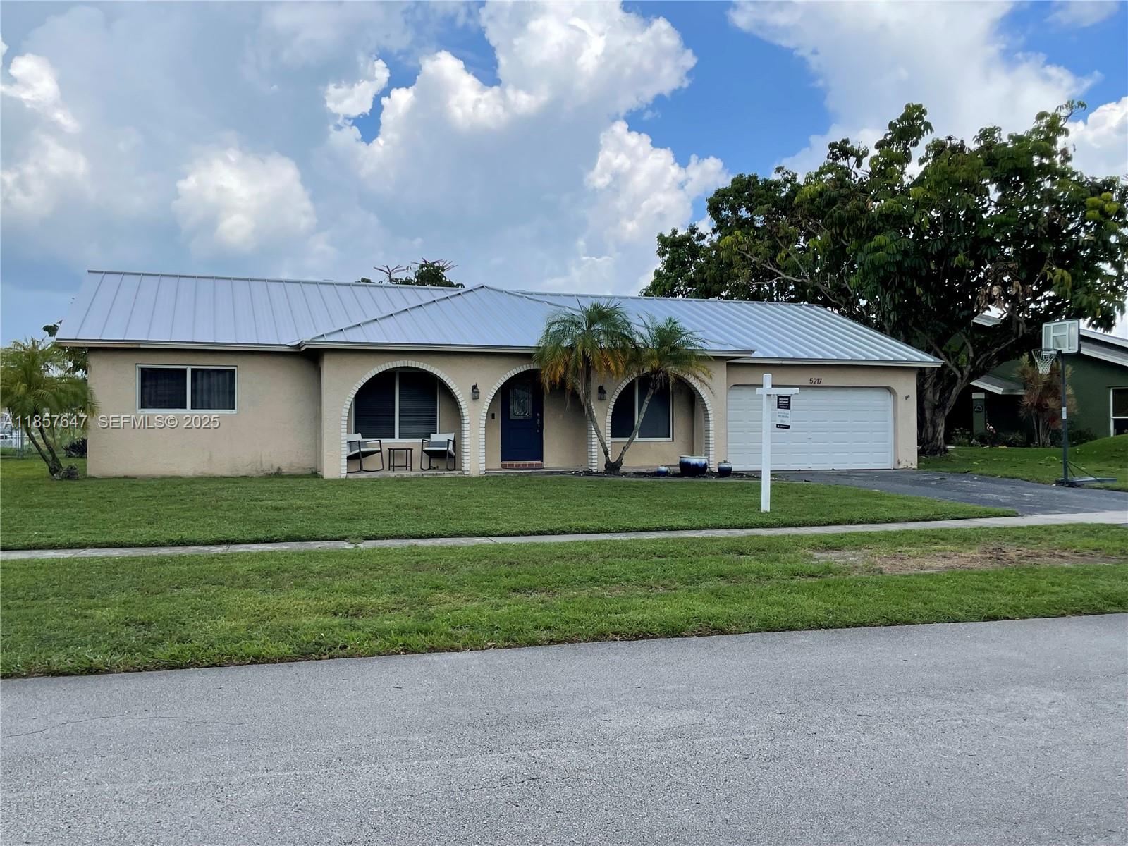 5217 Southwest 87th Avenue Cooper City, FL 33328 - Photo 2 of 8 a front view of a house with a garden and trees